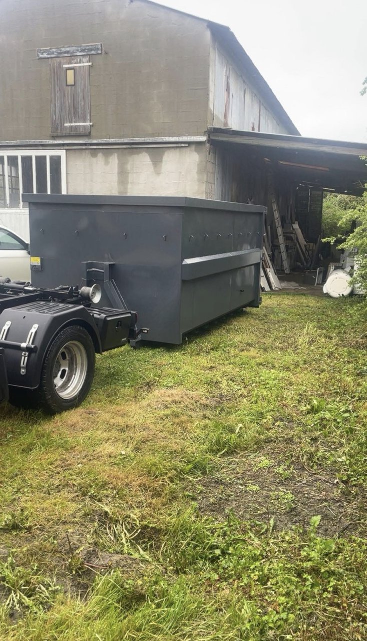 Grande benne 12 m³ grise posée devant un bâtiment industriel