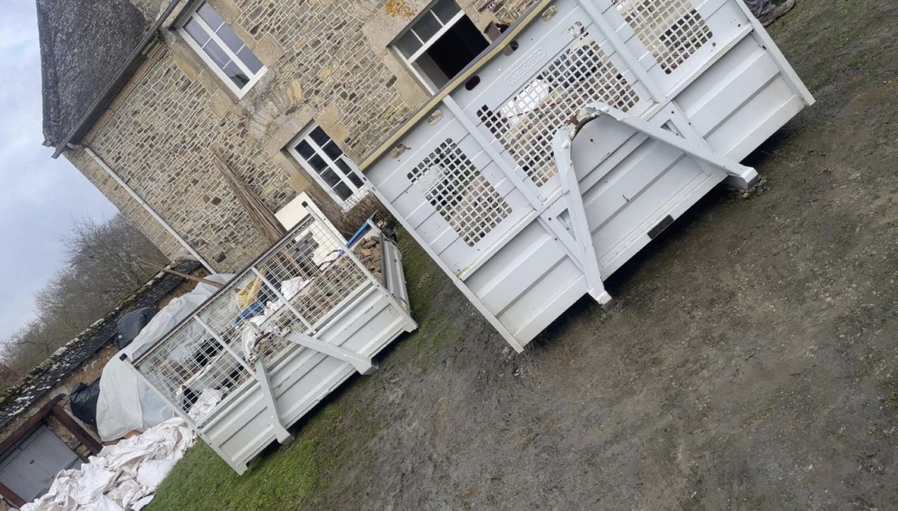 Bennes 3 m³ blanches à ridelles grillagées devant une maison en pierre