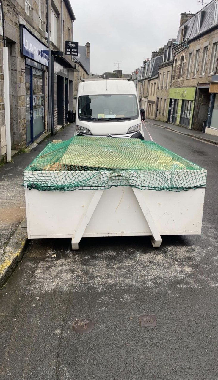 Benne 5 m³ chargée sur le camion, bâchée avec un filet vert, dans une rue du Loiret